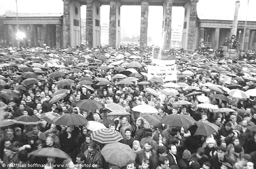 Mauerfoto: Menschenmasse mit vielen Regenschirmen bei der Ã–ffnung des Brandenburger Tors, welches im Hintergrund zu sehen ist.